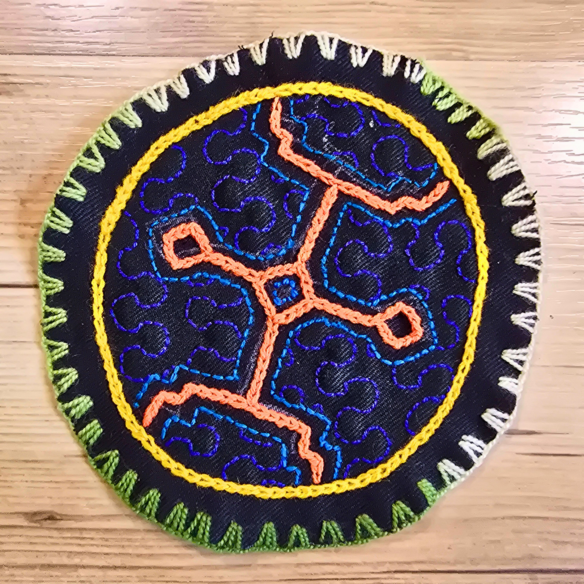 Hand-embroidered Shipibo textile in deep blue tones. A small round accent perfect for home decor, boho tables, or as an artisanal coaster.
