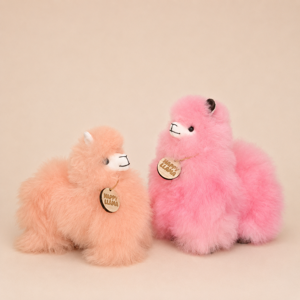Peach Blush mini baby alpaca llama beside pink Happy Llama