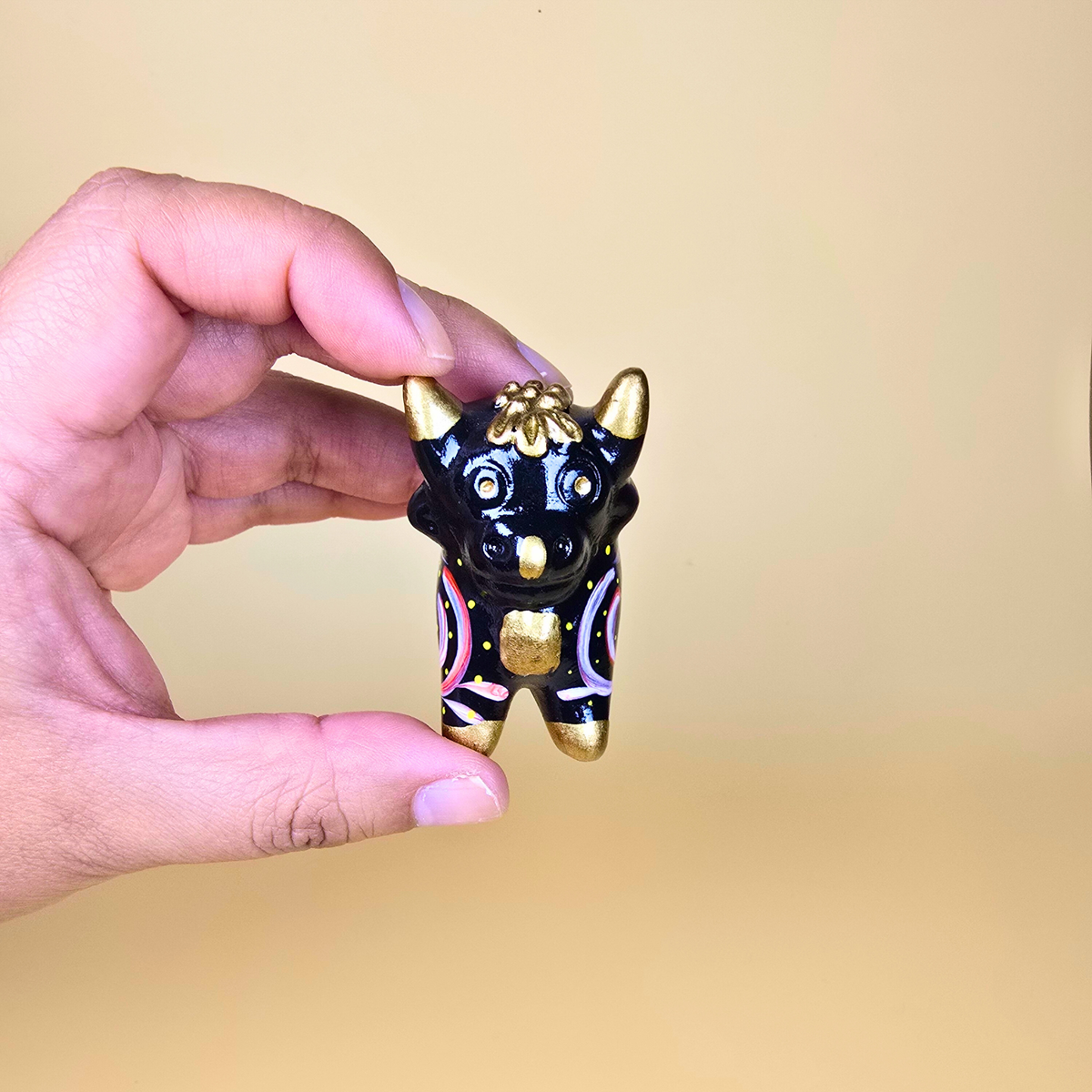 Small black Torito de Pucará held in hand to show its size